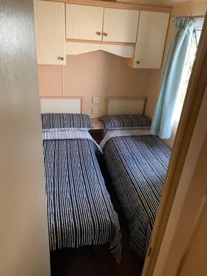 two beds in a small room with white cabinets at 1 Martello Beach 8 berth holiday home with pools in Clacton-on-Sea