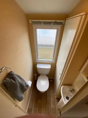 a small bathroom with a toilet and a window at 1 Martello Beach 8 berth holiday home with pools in Clacton-on-Sea