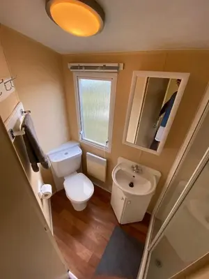 a small bathroom with a toilet and a sink at 1 Martello Beach 8 berth holiday home with pools in Clacton-on-Sea