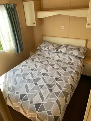 a bedroom with a bed with a gray and white comforter at 1 Martello Beach 8 berth holiday home with pools in Clacton-on-Sea