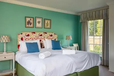 a bedroom with a large bed with blue walls at Abbey House by Group Retreats in Saffron Walden