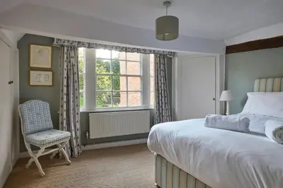a bedroom with a bed and a chair and a window at Abbey House by Group Retreats in Saffron Walden