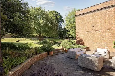 a patio with two chairs and a brick wall at Abbey House by Group Retreats in Saffron Walden