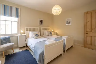 a bedroom with two beds and a chair and a window at Shore View, Aldeburgh - A lovely Seafront House on famous Crag Path with uninterrupted Beach Views - Aldeburgh Coastal Cottages in Aldeburgh