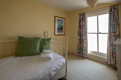 a bedroom with a bed with green pillows and a window at Shore View, Aldeburgh - A lovely Seafront House on famous Crag Path with uninterrupted Beach Views - Aldeburgh Coastal Cottages in Aldeburgh