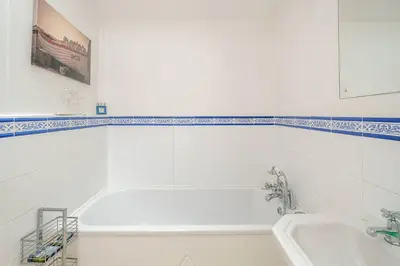 a white bathroom with a tub and a sink at Shore View, Aldeburgh - A lovely Seafront House on famous Crag Path with uninterrupted Beach Views - Aldeburgh Coastal Cottages in Aldeburgh