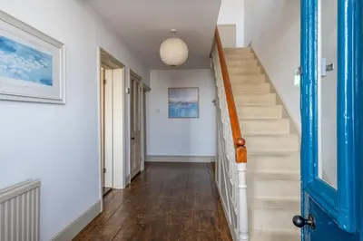 a hallway with stairs and a blue door at Shore View, Aldeburgh - A lovely Seafront House on famous Crag Path with uninterrupted Beach Views - Aldeburgh Coastal Cottages in Aldeburgh