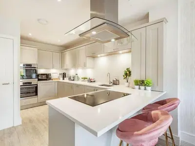 a white kitchen with a sink and two bar stools at Violet Place in Broomfield