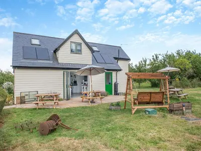 a house with a yard with picnic tables and umbrellas at Russets in North Weald