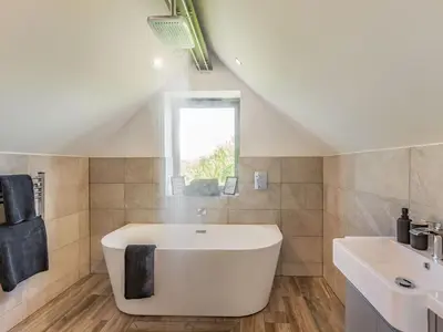 a bathroom with a white tub and a sink at Russets in North Weald