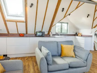 a living room with a couch and a kitchen at Russets in North Weald