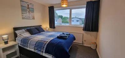 a bedroom with a bed with a blue blanket and a window at Shirley L, Milton, Cambridge, 4 BR House, Newly Refurbished in Milton