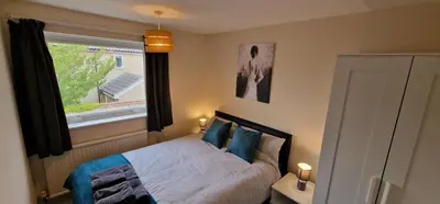 a bedroom with a bed with blue pillows and a window at Shirley L, Milton, Cambridge, 4 BR House, Newly Refurbished in Milton