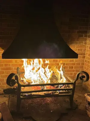 a fire burns in a brick fireplace with a bench at Farmhouse Retreat with Hot Tub, Pool, Horses, Games Room, Free Car Park, Only 45 min from Oxford Circus in Stapleford Tawney
