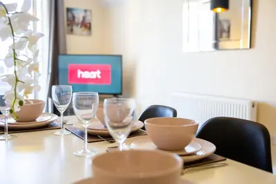 a table with chairs and wine glasses on it at Velvet 1-bedroom penthouse, Clockhouse, Hoddesdon in Hoddesdon
