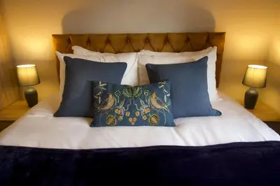 a bed with blue and white pillows and two lamps at Modern 3 Bed House with Garden and Parking in Cambridge