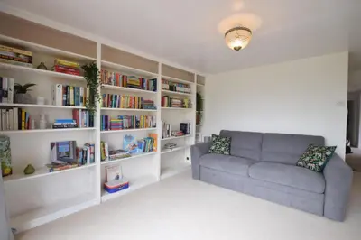 a living room with a couch and bookshelves at Skelder, Parham in Parham