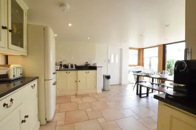 a kitchen with white cabinets and a table in it at Skelder, Parham in Parham