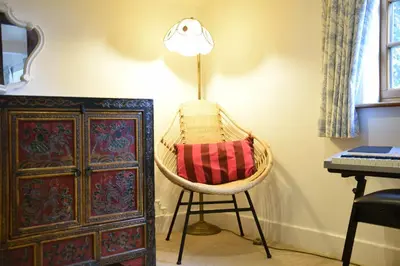 a chair with a red pillow sitting next to a lamp at Skelder, Parham in Parham