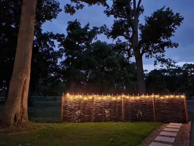 a fence with lights in a park at night at The Owls Rest Shepherds Hut Hethel in Norwich