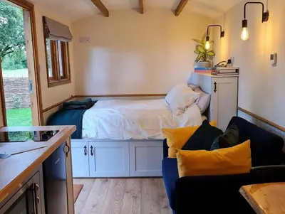 a small bedroom with a bed and a couch at The Owls Rest Shepherds Hut Hethel in Norwich