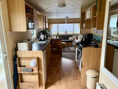 a small kitchen with wooden cabinets and a stove at Shell Beach Holiday Home Mersea Coopers Beach in East Mersea