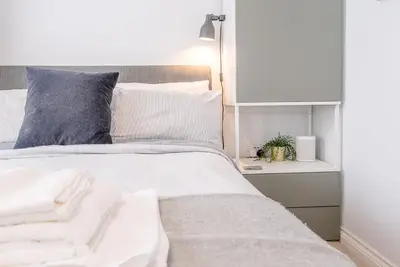 a bedroom with a bed with white sheets and a nightstand at Martlet Cottage Aldeburgh in Aldeburgh