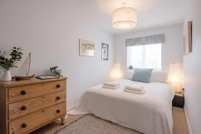 a bedroom with a bed and a dresser and a window at Martlet Cottage Aldeburgh in Aldeburgh