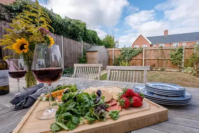 a table with a plate of food and a glass of wine at Martlet Cottage Aldeburgh in Aldeburgh