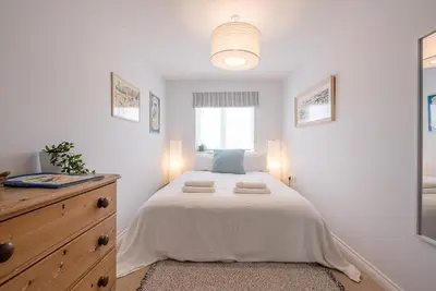 a white bedroom with a bed and a window at Martlet Cottage Aldeburgh in Aldeburgh