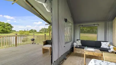 a screened in porch with a couch on a deck at Finest Retreats - The Herdwick Safari Tent in Hertford