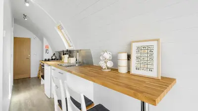 a kitchen with white cabinets and a wooden counter top at Finest Retreats - The Highland Camping Pod in Hertford