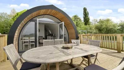 a wooden deck with a table and a circular archway at Finest Retreats - The Highland Camping Pod in Hertford