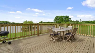 a table and chairs on a deck with a grill at Finest Retreats - The Chicken Coop in Hertford