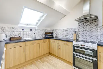a kitchen with wooden cabinets and a window at The Old Warehouse Ely in Ely