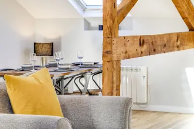 a dining room with a table and a yellow pillow at The Old Warehouse Ely in Ely