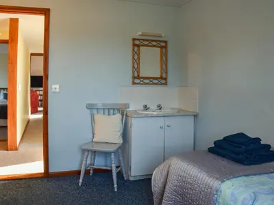a bathroom with a sink and a chair next to a bed at Leys Barn in Great Chishall