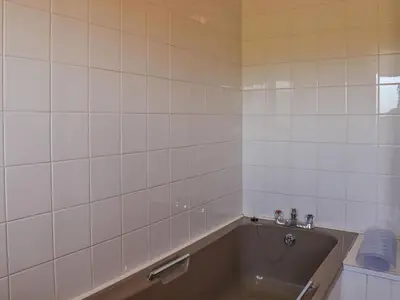 a bath tub in a bathroom with white tiles at Leys Barn in Great Chishall