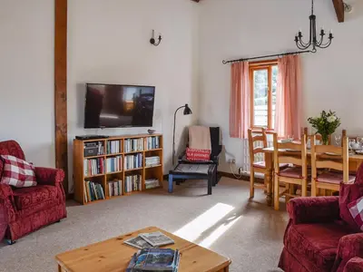 a living room with a table and a dining room at Leys Barn in Great Chishall