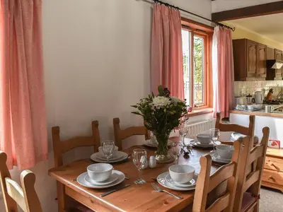 a dining room with a wooden table with flowers on it at Leys Barn in Great Chishall