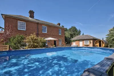 a large swimming pool in front of a brick house at Harkstead Hall By Group Retreats in Ipswich