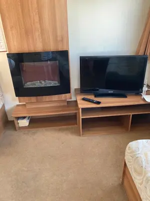 a living room with a large television on a wooden entertainment center at Luxury 8 and 6 berth caravans in Jaywick Sands