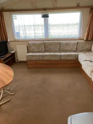 a living room with a couch in front of a window at Luxury 8 and 6 berth caravans in Jaywick Sands
