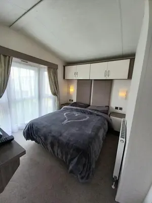 a bedroom with a large bed and a large window at Luxury 8 and 6 berth caravans in Jaywick Sands