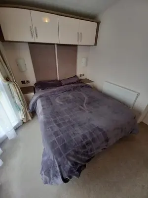 a bedroom with a bed with a purple comforter at Luxury 8 and 6 berth caravans in Jaywick Sands