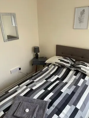 a bedroom with a bed with a striped blanket and a mirror at Sea Breeze in Harwich