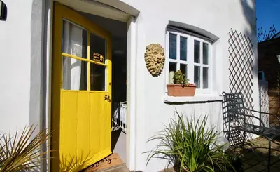 a yellow door on a white house with a window at The Cottage at Barkwith House in Leiston