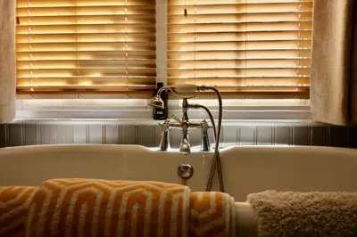 a bath tub with two towels and a window at The Cottage at Barkwith House in Leiston