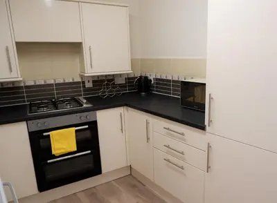 a kitchen with white cabinets and a stove top oven at Colchester Sunny Apartment with Pool and EV Car Point in Lexden