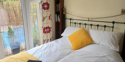 a bed with a yellow pillow on it next to a window at Colchester Sunny Apartment with Pool and EV Car Point in Lexden